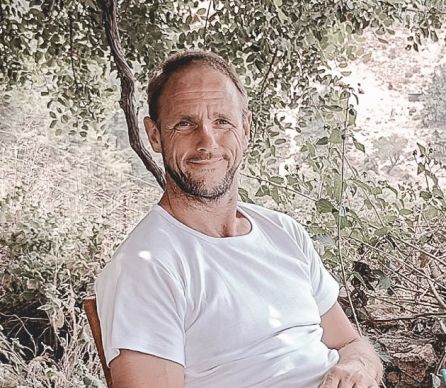 Stephan Röhrs in einem weißen Shirt vor Blumen